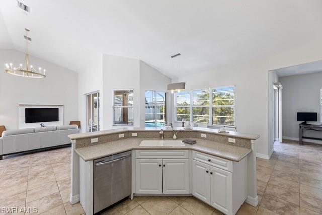 Open-concept kitchen and living area featuring a curved island with stainless steel appliances, white cabinetry with hardware accents, and tile flooring throughout