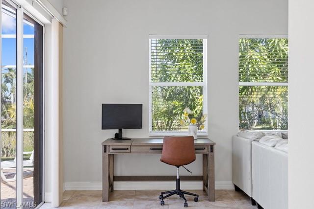 Bright home office featuring a wood-finish desk with integrated storage, comfortable task seating, and a flat-screen monitor setup