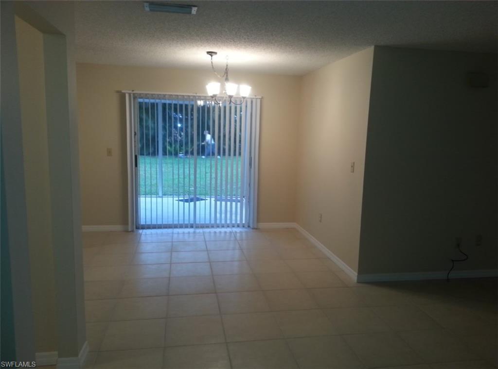 Spare room featuring a textured ceiling, tile patterned floors, and a notable chandelier