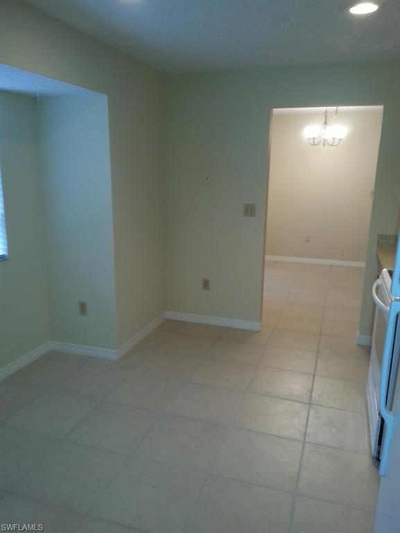 Unfurnished room with light tile patterned floors and an inviting chandelier