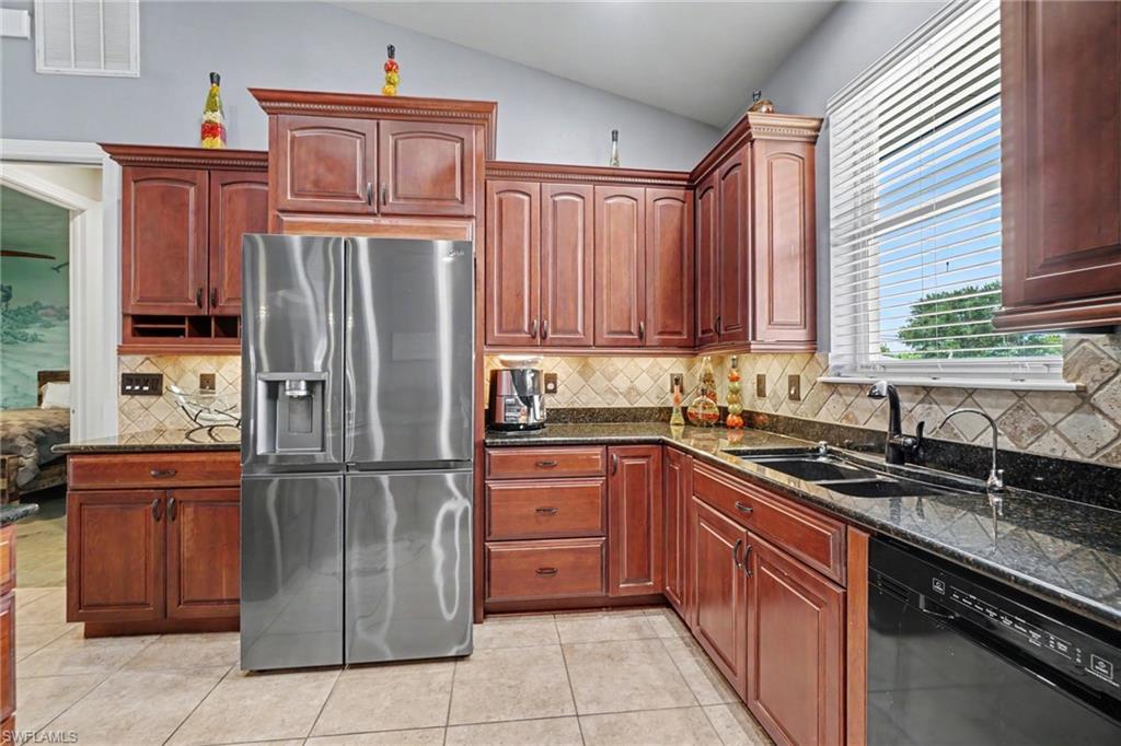 Kitchen featuring rich wood cabinetry, dark granite countertops, and a full suite of stainless steel and black appliances