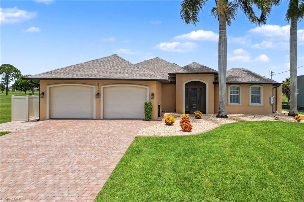 Mediterranean-style facade featuring an arched entry, two-car garage, and a paver driveway