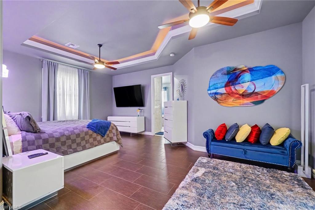 Spacious room with tray ceiling featuring recessed lighting and two ceiling fans