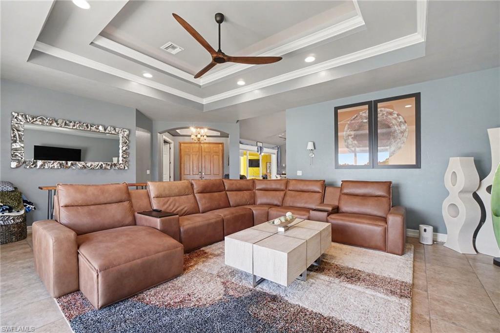 Tray ceiling with recessed lighting and a ceiling fan, complemented by tile flooring