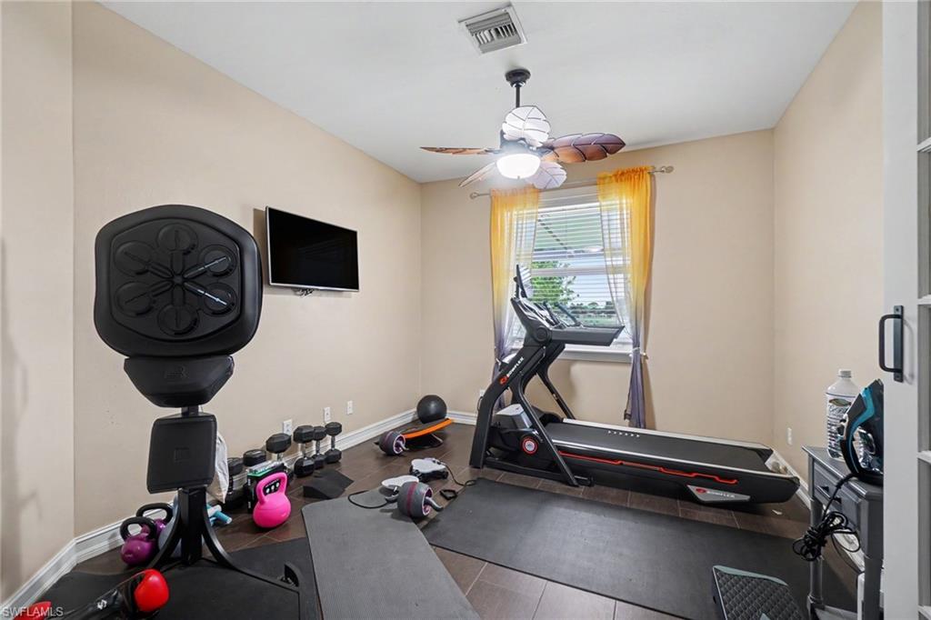 Room featuring wood-finish flooring, a ceiling fan with integrated lighting, and a single window with blinds