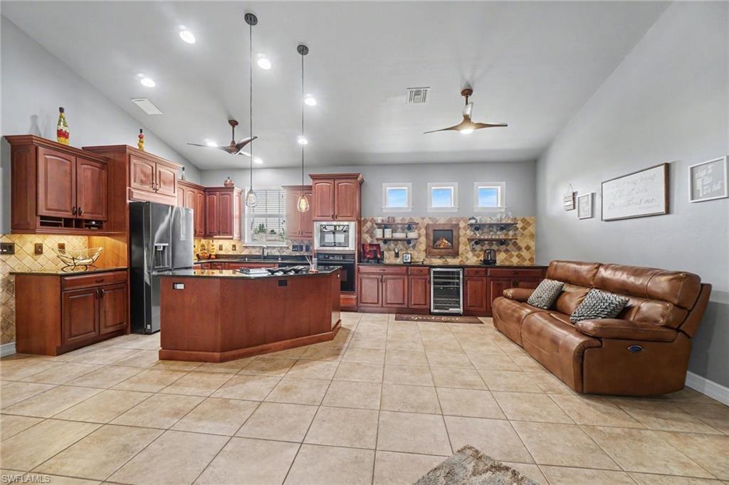 Spacious kitchen and entertaining area featuring a large center island, recessed lighting, tile flooring, and vaulted ceilings