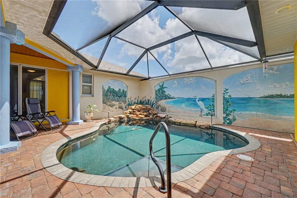 Screened-in patio featuring a built-in swimming pool with a rock waterfall feature, brick paver decking, and a custom mural wall