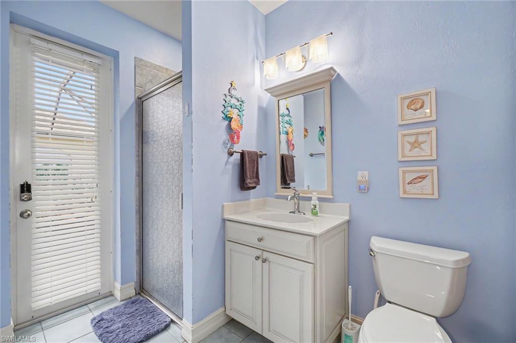 Bathroom featuring a glass-enclosed shower, white vanity with integrated sink, and a commode
