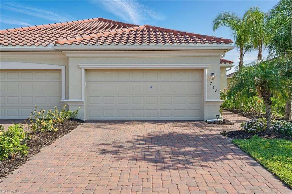 Exterior featuring a terracotta tile roof, stucco facade, and an attached two-car garage with panel doors