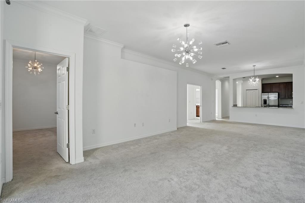 Living room and Dining Area; neutral wall finishes, polished concrete flooring, contemporary pendant lighting fixtures, and direct sightlines to the kitchen with stainless steel appliances and white cabinetry