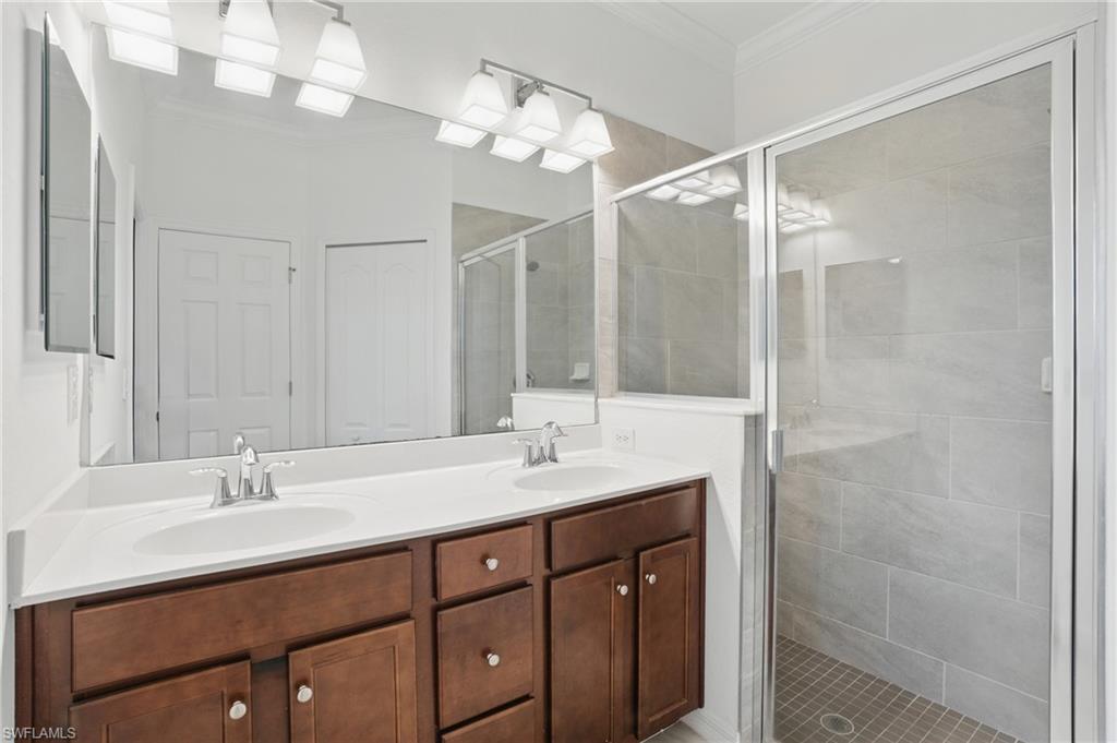 Dual vanity with wood-finish cabinetry, white countertop, and brushed nickel fixtures