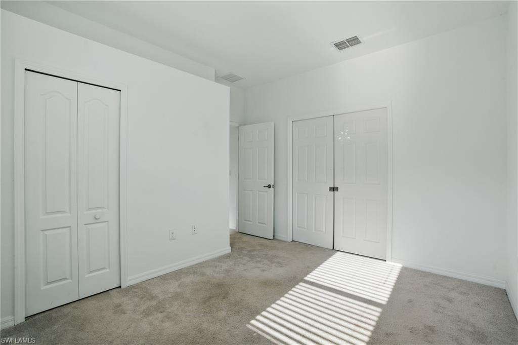 Carpeted room featuring white walls, bi-fold closet doors, and Pocket doors to the living room area