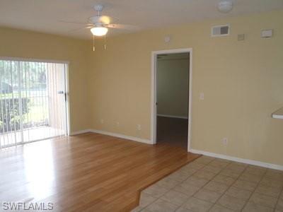 Spacious living area featuring wood-finish flooring, light-toned walls, and a ceiling fan with integrated lighting