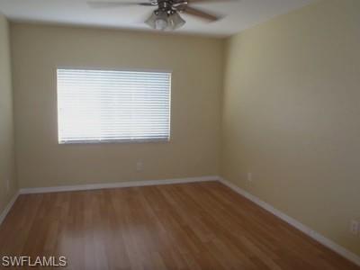 Spacious bedroom featuring wood-finish flooring, neutral wall finishes, ceiling fan with integrated lighting, and a large window with horizontal blinds providing natural light
