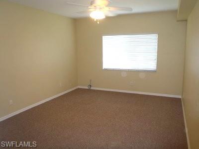 Spacious bedroom featuring neutral wall finishes, carpet flooring, a ceiling fan with integrated lighting, and a large window with horizontal blinds providing natural light