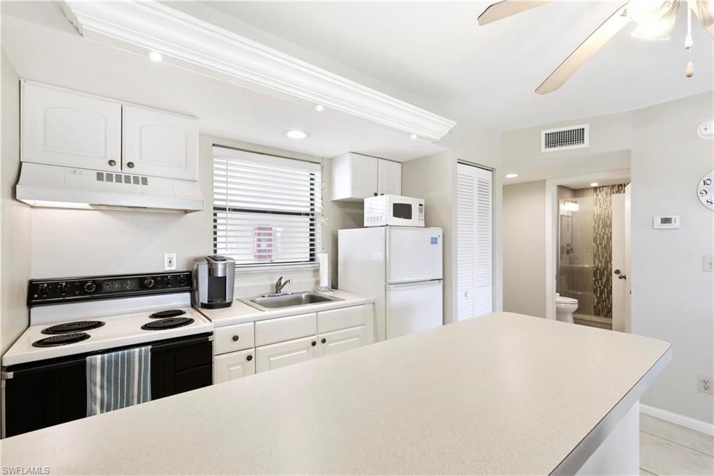Kitchen with ceiling fan, white appliances, and white cabinetry