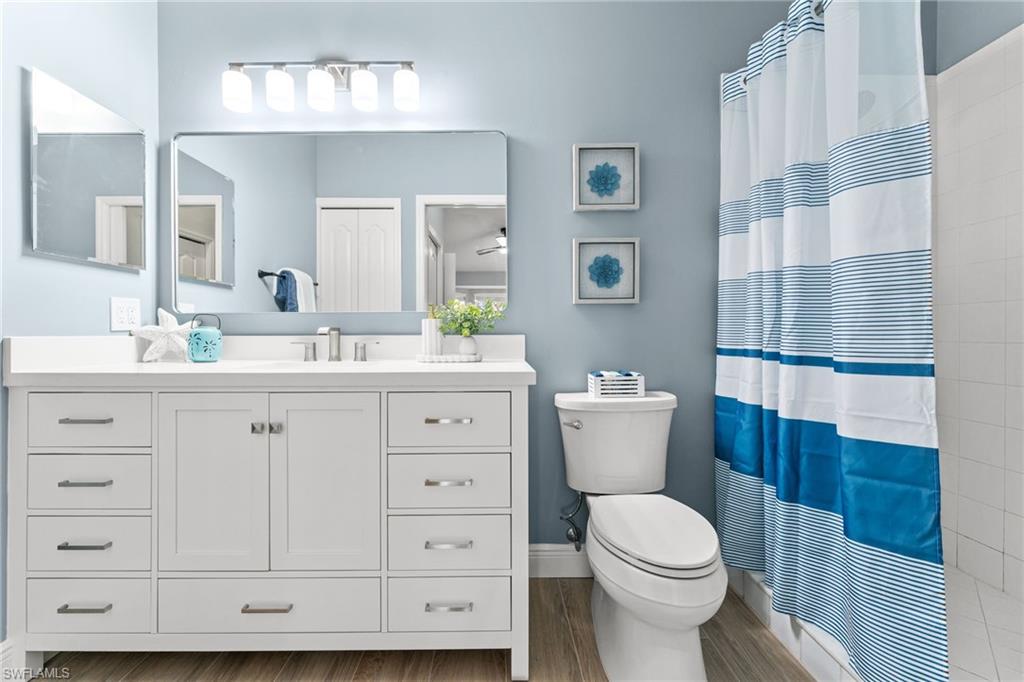 The tile floor and baseboards carried into bathroom. New toilet, vanity, light fixtures, mirror, electric, SW stardew blue paint. The bathroom also has a linen closet for more storage.