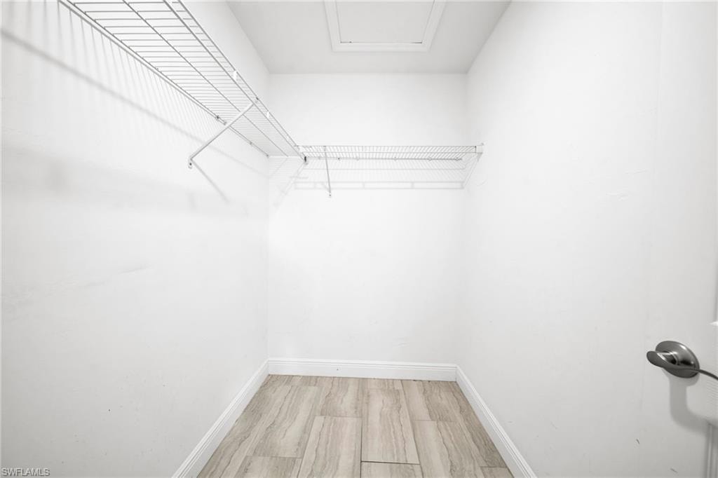 Walk-in closet with wire shelving, wood-finish flooring, white walls, and a ceiling access panel