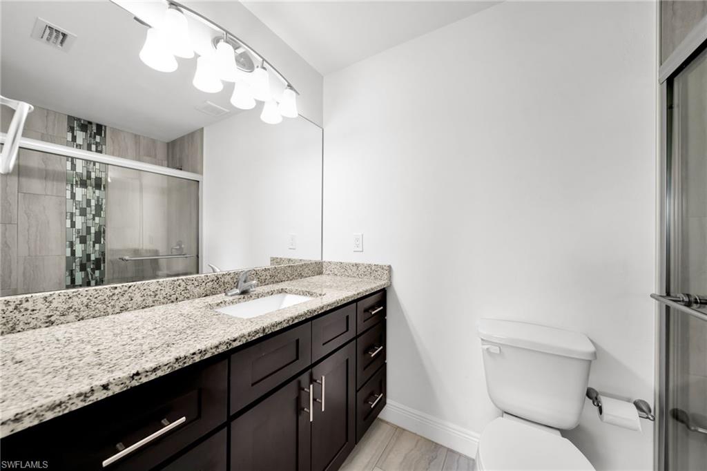 Bathroom featuring a dark wood vanity with a granite countertop, undermount sink, and a large mirror