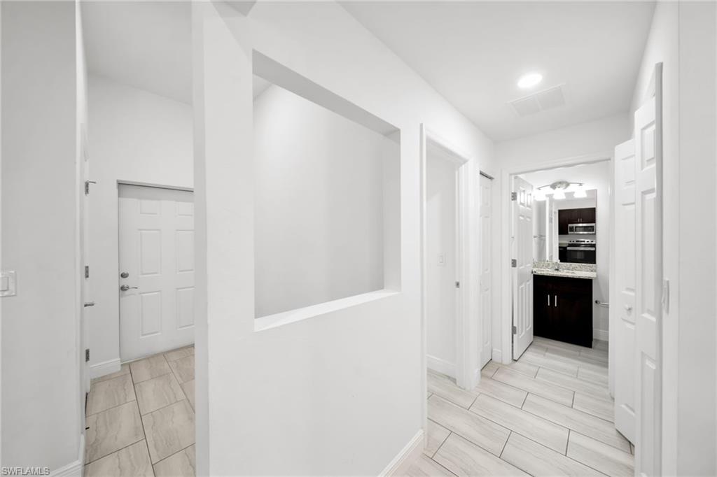 Hallway with light-toned rectangular tile flooring, recessed lighting, and a decorative wall niche