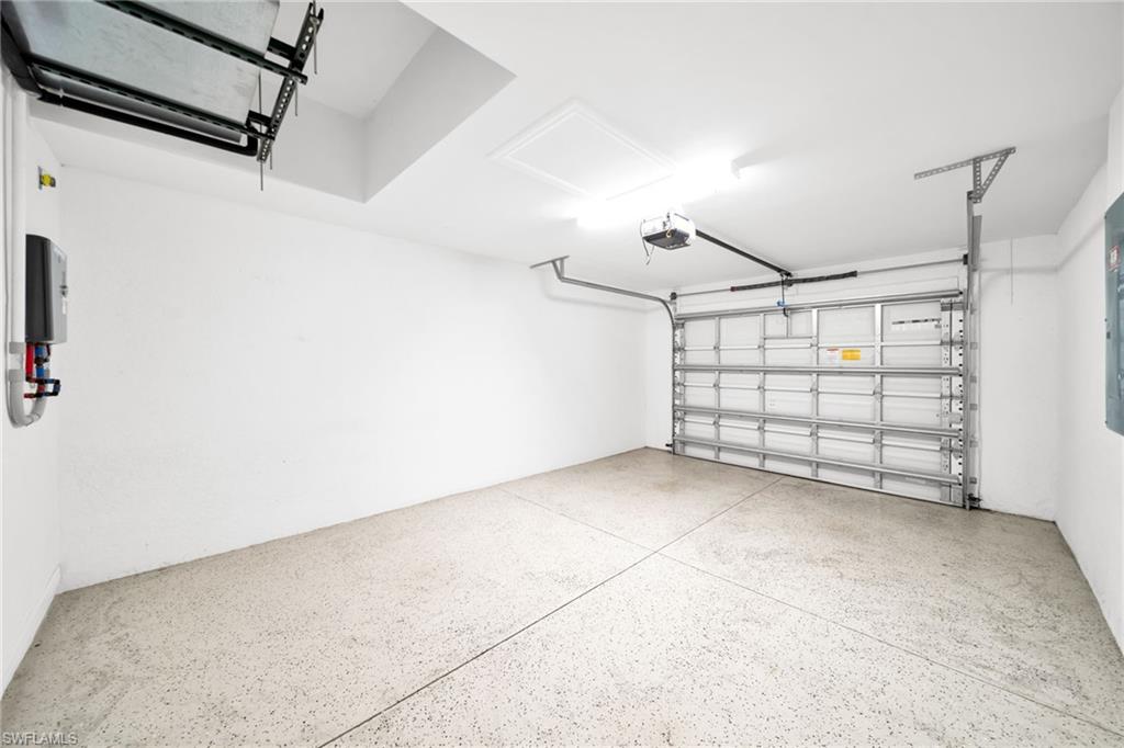 Bright, spacious garage featuring an automatic door opener, smooth white walls, durable epoxy flooring, and recessed ceiling lighting