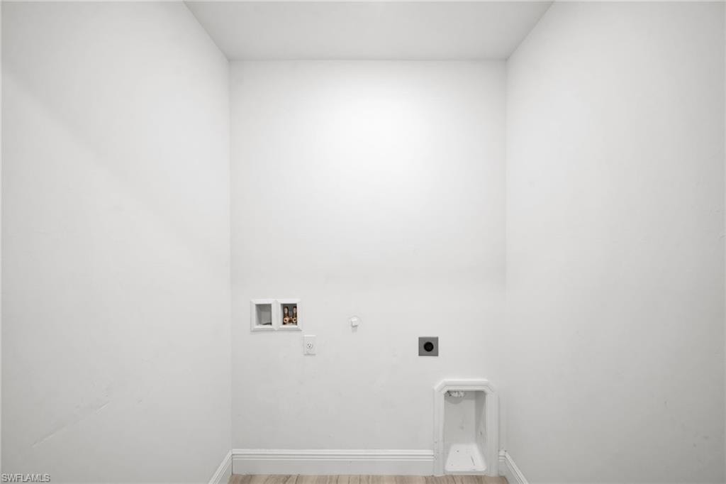 Dedicated utility room with light wood-finish flooring and white baseboards