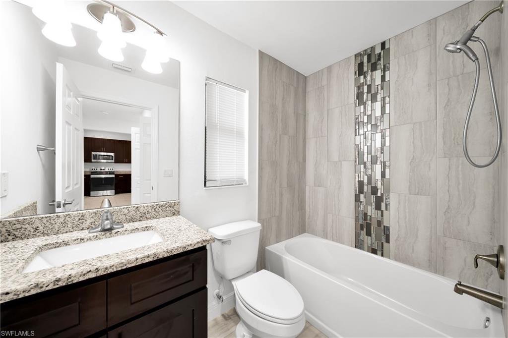 Bathroom featuring a white bathtub, light-toned wall tile, and decorative mosaic tile accent