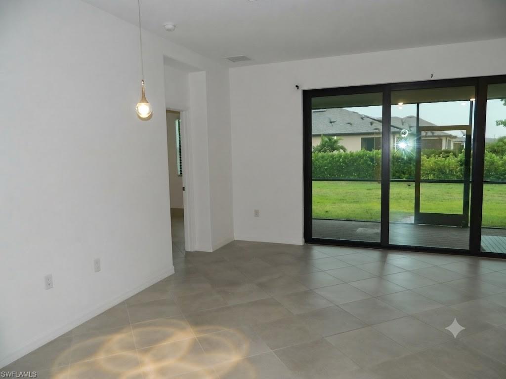 Spacious interior with large format tile flooring and a modern pendant light fixture