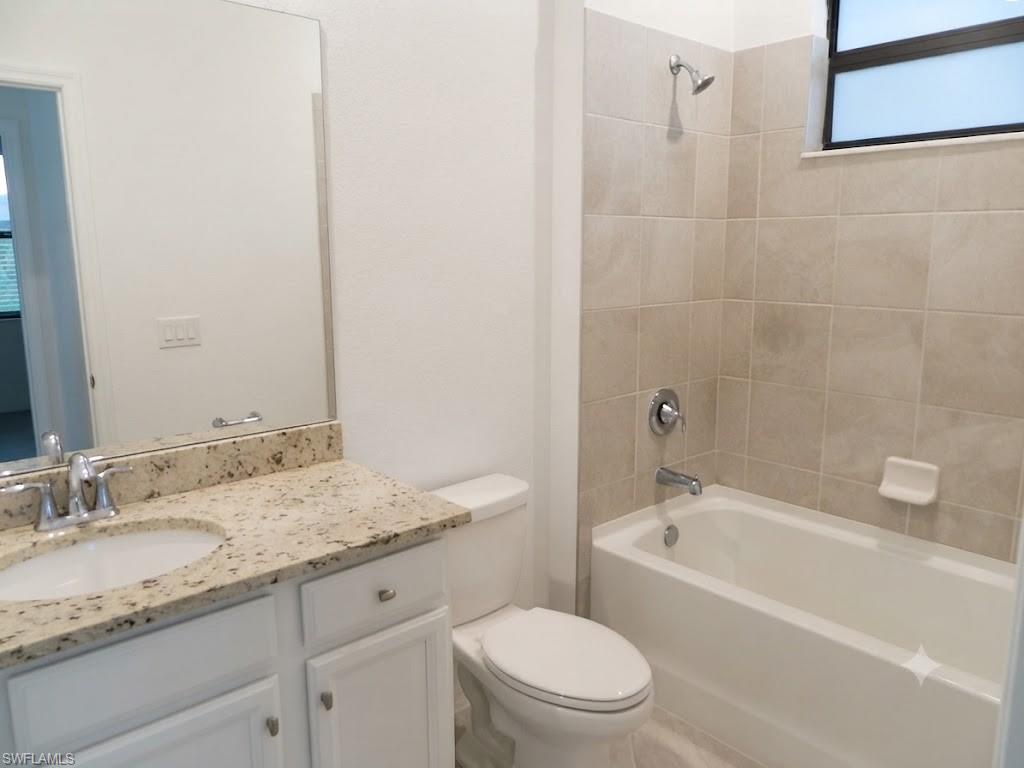 Full bathroom featuring a white vanity with a granite countertop, undermount sink, and chrome fixtures