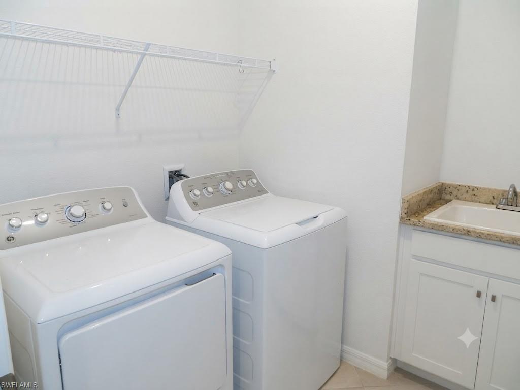 Dedicated laundry room featuring side-by-side washer and dryer with control-panel tops, white cabinetry with granite-style countertop, and ample storage