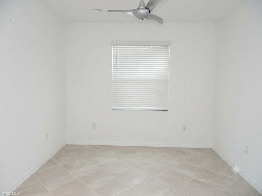 Bright interior space featuring light-colored tile flooring, white walls, and a window with horizontal blinds