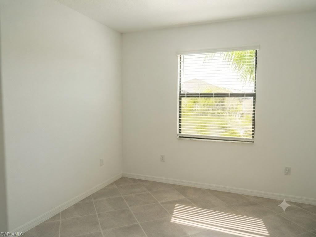 Neutral white walls and tiled flooring featuring a single window with blinds
