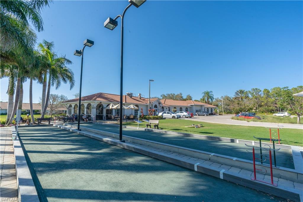 Bocce ball court with integrated lighting, surrounding palm trees, and a distant clubhouse with outdoor seating