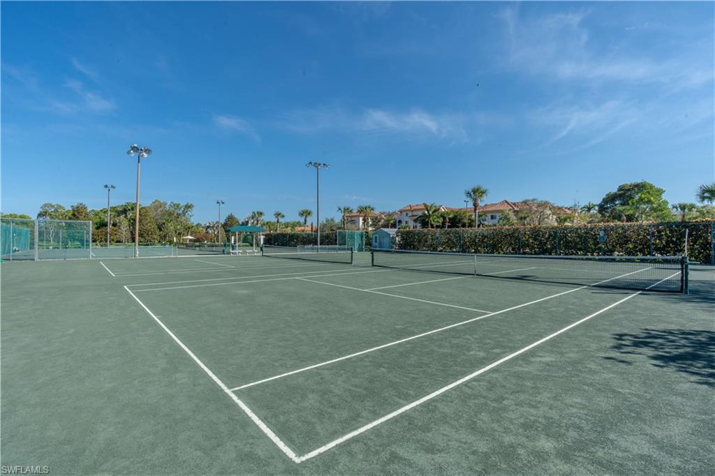 Two tennis courts featuring netting, perimeter fencing, and overhead lighting