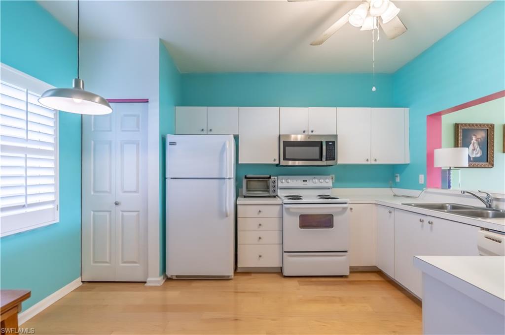 Kitchen featuring white cabinetry, light wood-finish flooring, a stainless steel microwave, and a double basin sink