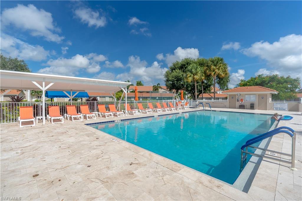 Swimming pool with tile surround, sun shade structure, and a poolside building