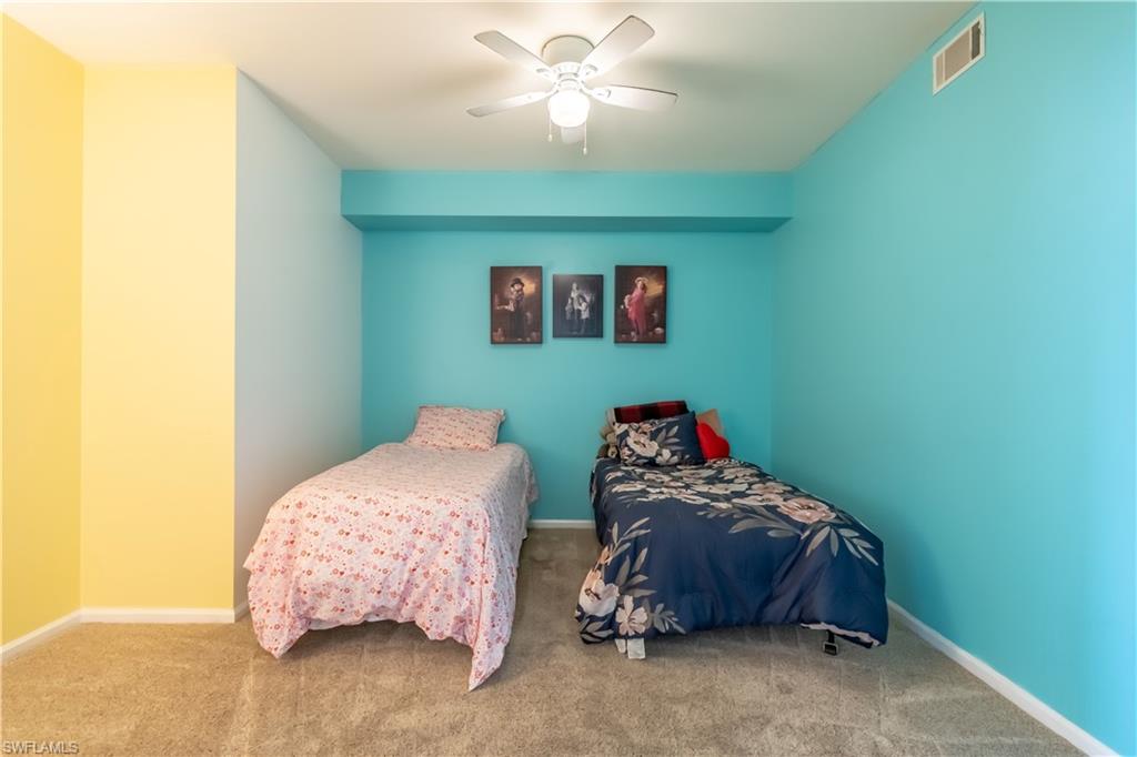 Neutral-toned carpet flooring with a ceiling fan light fixture and colorful wall finishes