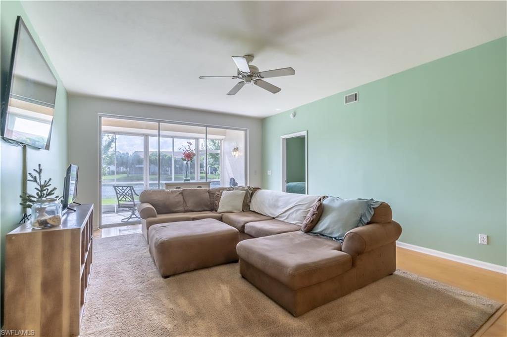Sliding glass doors opening to a screened-in patio, ceiling fan, and light-toned flooring