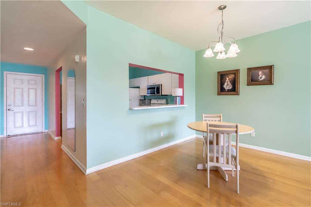 Wood-finish flooring throughout, a dining area with a chandelier, and a pass-through window to the kitchen
