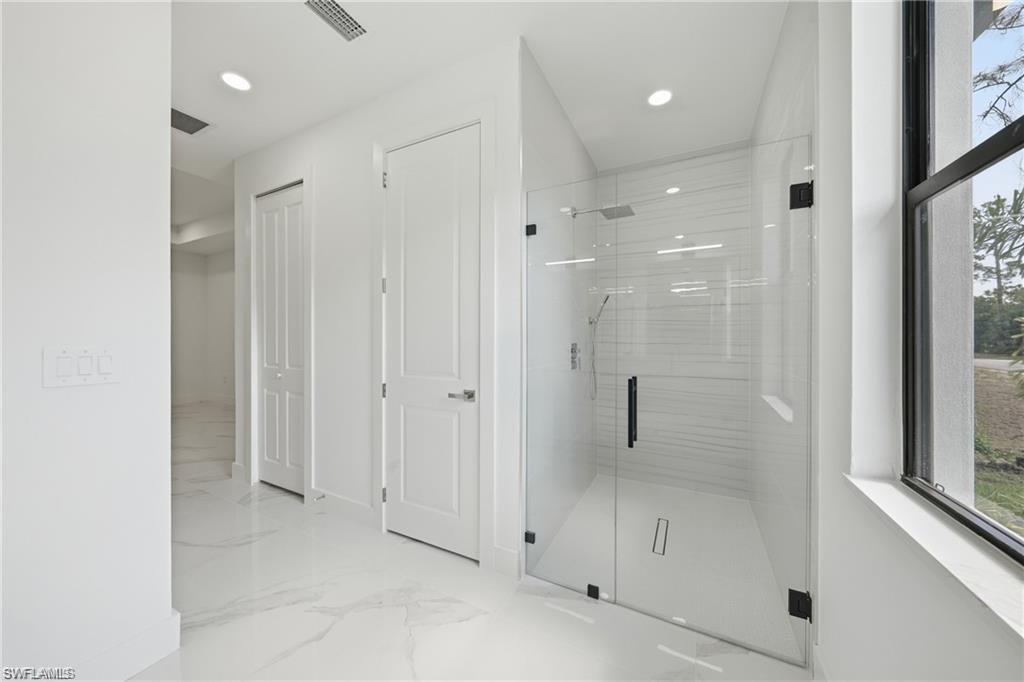 Walk-in shower with clear glass enclosure and black hardware, featuring a rainfall showerhead