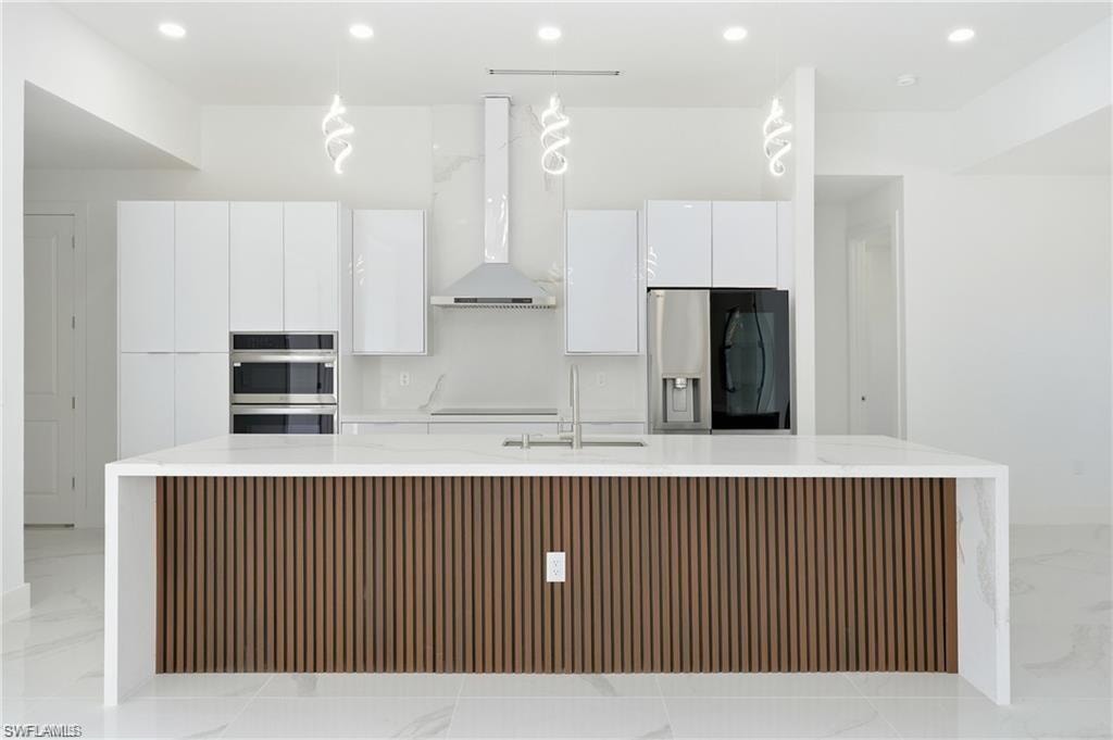 Kitchen featuring a waterfall island with wood-finish paneling, stainless steel appliances, built-in double ovens, and recessed lighting