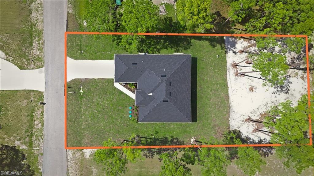 Single-family residence with a dark shingle roof, concrete driveway, and expansive lawn