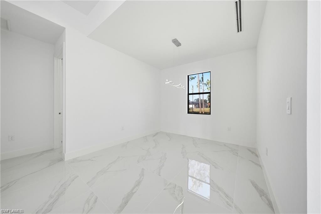 Spacious interior featuring white walls, large format tile flooring, and a window with a black frame