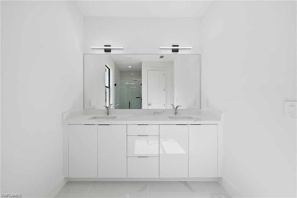 Dual vanity with white cabinetry and integrated sinks, under a large mirror and two horizontal light fixtures