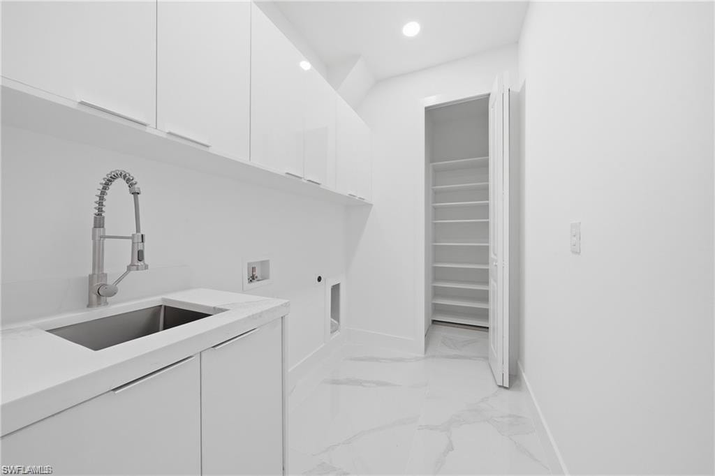White cabinetry, stainless steel sink, pull-down faucet, white countertop, and tiled flooring