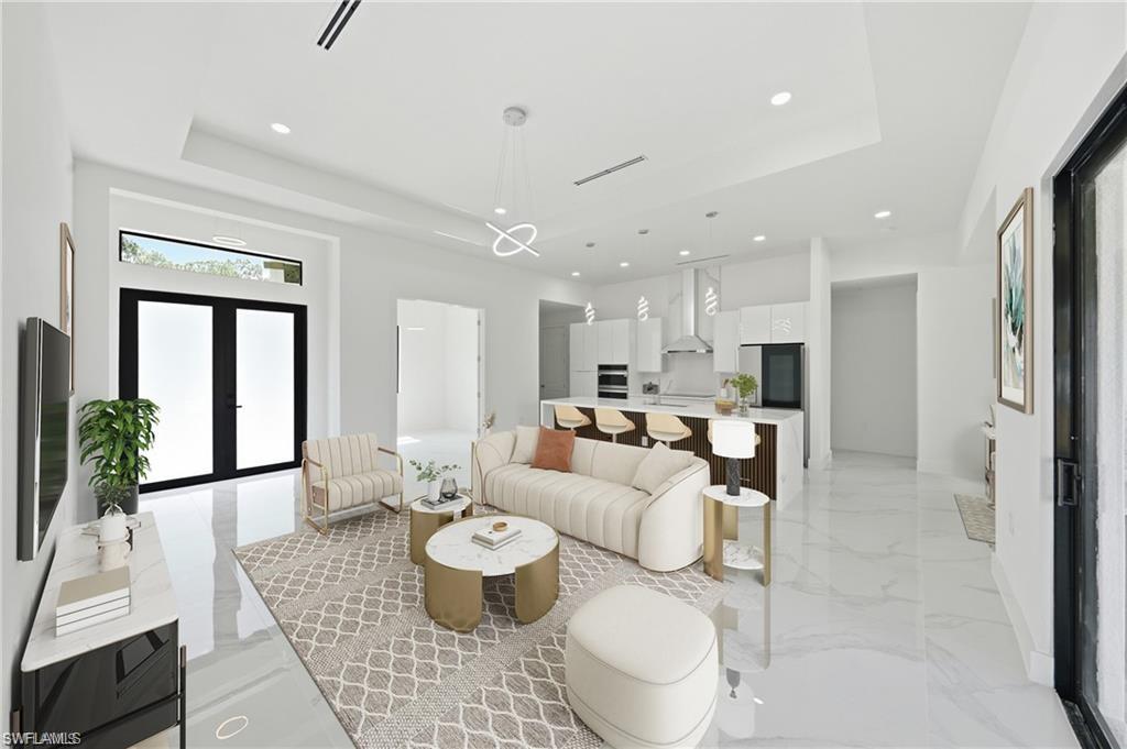 Open-concept living space featuring high ceilings, large format tile flooring, a modern kitchen with a waterfall island, and recessed lighting