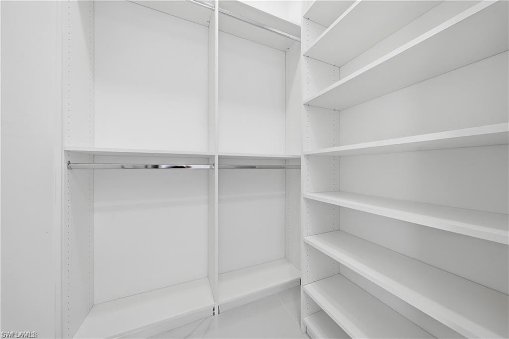 Walk-in closet with extensive built-in shelving, multiple hanging rods, and adjustable shelf heights
