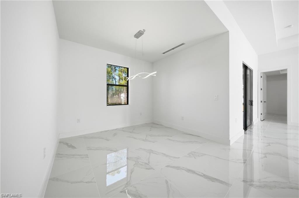 Sleek interior featuring white walls, large format tile flooring, a modern linear chandelier, and a black-framed window