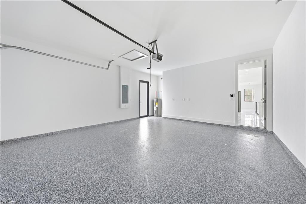 Spacious garage featuring a durable speckled epoxy floor, white walls, and an overhead garage door mechanism