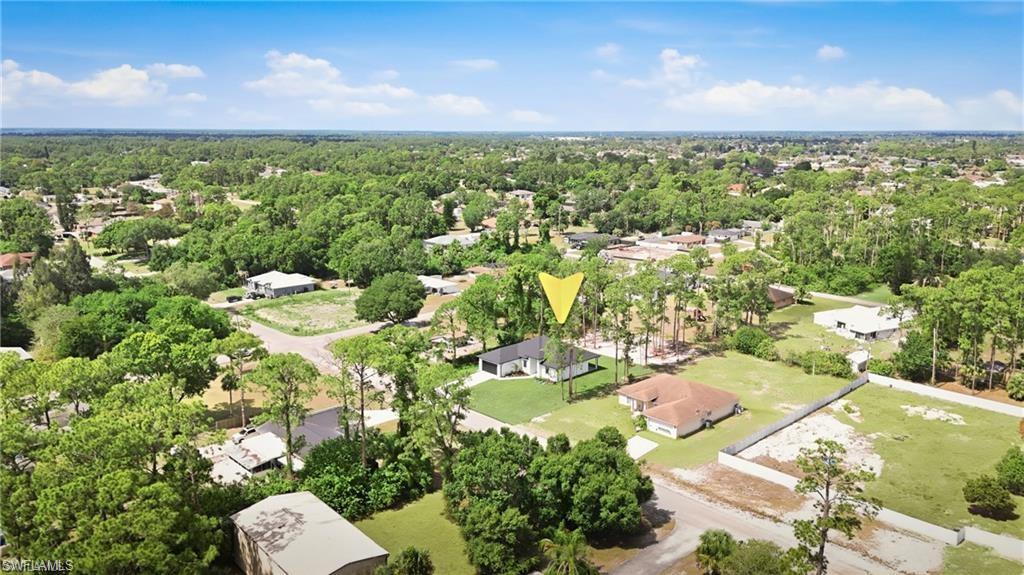 Aerial perspective showcasing a residential lot with a single-story structure and surrounding green landscaping